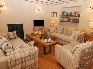 A living room with sofas a wooden coffee table a television and shelves with books at 1 Cheriton Row in Carew Cheriton Nr Tenby Pembrokeshire