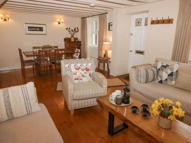 A living room with wooden dining table chairs armchairs a sofa coffee table and a lamp at 1 Cheriton Row Carew Cheriton Nr Tenby Pembrokeshire