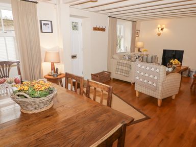 A living room with wooden dining table and chairs a sofa and armchair near a fireplace at 1 Cheriton Row Carew Cheriton Nr Tenby Pembrokeshire