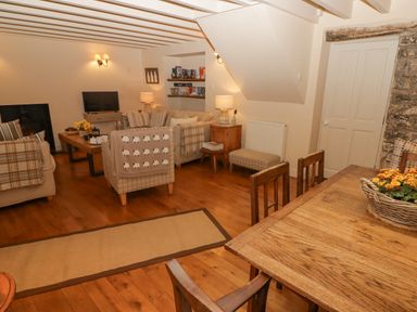 A living room with beige sofas a wooden dining table and chairs and a television at 1 Cheriton Row Carew Cheriton Nr Tenby Pembrokeshire