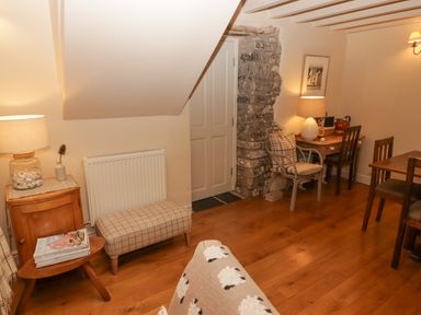 A room with wooden floor a small wooden table with magazines a checkered bench a wooden desk with a lamp and chairs at 1 Cheriton Row Carew Cheriton Nr Tenby Pembrokeshire