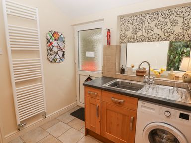 A kitchen area with a sink wooden cabinets washing machine and a door with a window at 1 Cheriton Row Carew Cheriton Nr Tenby Pembrokeshire