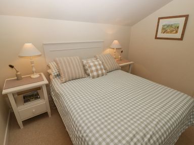 A bedroom with a double bed green and white checked bedspread two bedside tables with lamps and a framed picture on the wall at 1 Cheriton Row Carew Cheriton Nr Tenby Pembrokeshire