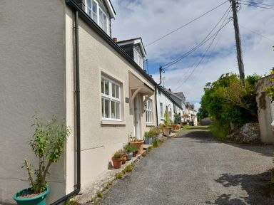 A row of cottages along a narrow paved street with potted plants and electricity wires overhead at 1 Cheriton Row Carew Cheriton Nr Tenby Pembrokeshire