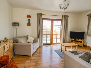 A living room with two sofas coffee table television and wooden cabinet at Beudy in Mwnt Cardigan Ceredigion