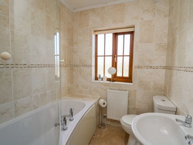 A bathroom with a bathtub sink toilet and window at Beudy in Mwnt Cardigan Ceredigion