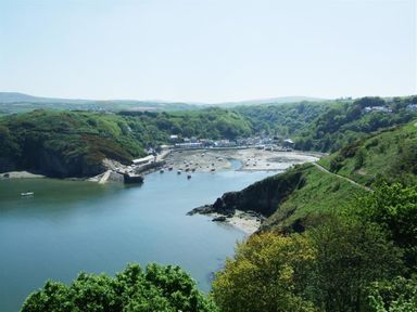 A river estuary with boats and a village surrounded by green hills and trees at Cable Cottage in Fishguard Pembrokeshire