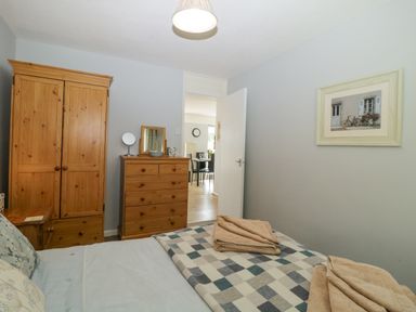 A bedroom with wooden wardrobe and chest of drawers and a bed with folded towels at 9 Manorcombe Bungalows in St Ann's Chapel near Callington