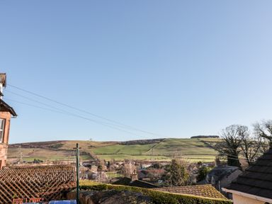 A view of rooftops trees and hills under a clear sky at Peth Head Cottage in Wooler