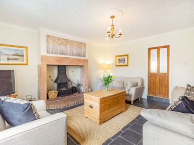 A living room with a fireplace wooden chest coffee table and sofas at Peth Head Cottage in Wooler