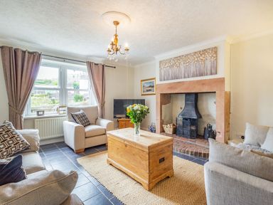 A living room with sofas a wooden chest coffee table a fireplace and a television at Peth Head Cottage in Wooler