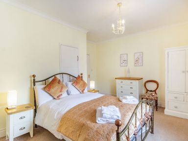A bedroom with a double bed a wooden chair a white chest of drawers and a wardrobe at Peth Head Cottage in Wooler