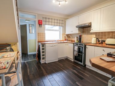 A kitchen with white cabinets wooden countertops and dining table at Scarborough Cottage in Driffield