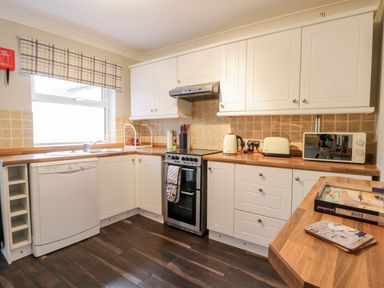 A kitchen with white cabinets dishwasher stove kettle toaster and microwave at Scarborough Cottage in Driffield