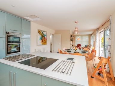 A kitchen with an island and cooktop leading to a dining area with a table and chairs at High Banks in Dartmouth