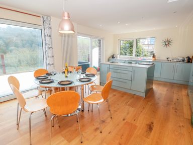A kitchen with a round dining table set for six with wooden chairs at High Banks in Dartmouth