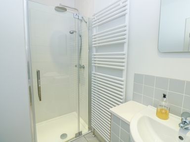 A bathroom with a glass shower enclosure a towel radiator a sink with soap at High Banks in Dartmouth