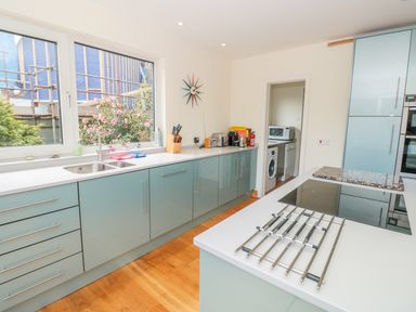 A kitchen with blue cabinets a window above the sink countertop appliances and a wooden floor at High Banks in Dartmouth