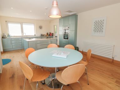 A kitchen with a round table and wooden chairs a blue cabinet unit and kitchen island at High Banks in Dartmouth