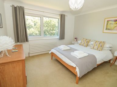 A bedroom with a double bed featuring folded towels bedside tables a wooden dresser and a window with curtains at High Banks in Dartmouth