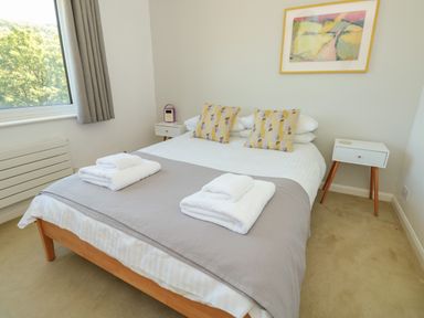 A bedroom with a double bed two pillows two bedside tables and a window at High Banks in Dartmouth