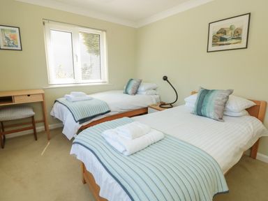 A bedroom with two single beds bedside table and framed pictures on the wall at High Banks in Dartmouth