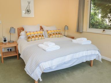 A bedroom with a bed with folded towels on it two bedside tables with lamps and a window with a curtain at High Banks Dartmouth