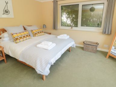 A bedroom with a double bed with pillows and towels next to a window and a wicker basket at High Banks in Dartmouth