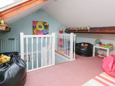 A playroom with bean bag chairs toys a small white table and a railing around stairs at Dalesway Cottage in Bowness-On-Windermere