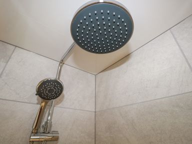 A shower head and handheld shower in a tiled shower at Dalesway Cottage in Bowness-On-Windermere