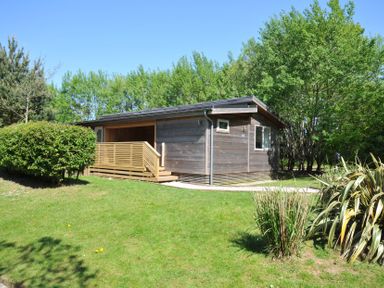 A wooden building with a deck in a grassy area at The Hideout in Lanreath