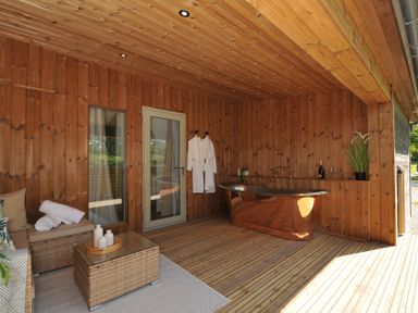 An outdoor area with a wooden bathtub and seating at The Hideout in Lanreath