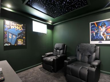A home theater with recliner chairs and sci-fi posters at The Hideout in Lanreath