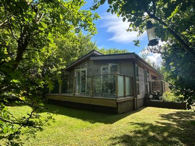 A house with a deck surrounded by trees at The Hideout in Lanreath