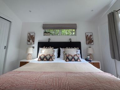 A bedroom with a bed and lamps on nightstands at The Hideout in Lanreath