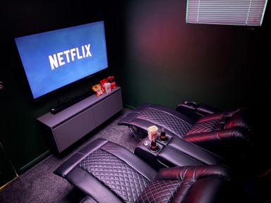 A home theater with recliners and a television displaying Netflix at The Hideout in Lanreath