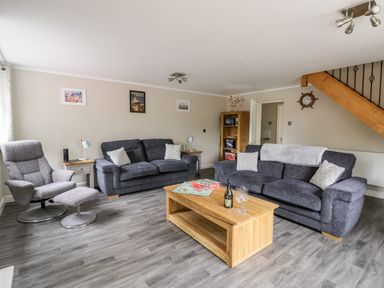 A living room with two sofas a chair a wooden coffee table and a staircase at Byefield Lodge in Welland