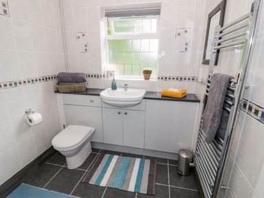 A bathroom with a toilet sink cabinet window and towel rack at Byefield Lodge in Welland