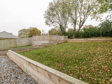 A fenced garden with a sloped grassy area and wooden retaining walls at Flat 2 38 Preston Road Weymouth