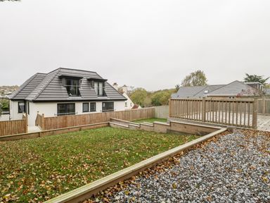 A fenced garden with grass and leaves next to a gravel area and a modern house at Flat 2 38 Preston Road Weymouth