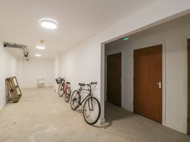 A storage room with two bicycles a white chair and a wooden frame near two wooden doors at Flat 2 38 Preston Road Weymouth