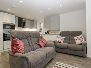A living room with two gray sofas and a modern kitchen in the background at Flat 2 38 Preston Road in Weymouth