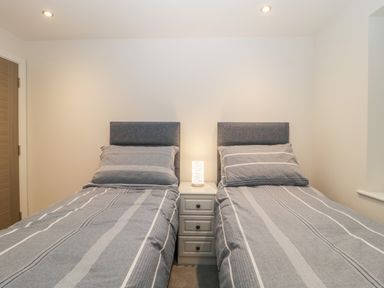 A bedroom with two single beds and a bedside table with a lamp at Flat 2 38 Preston Road Weymouth