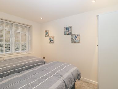 A bedroom with two single beds covered with striped bedding a window with blinds and sea life artwork on the wall at Flat 2 38 Preston Road Weymouth