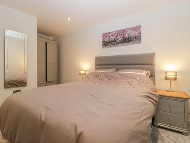 A bedroom with a bed a bedside table with lamp a wardrobe a wall mirror and a picture above the bed at Flat 2 38 Preston Road Weymouth