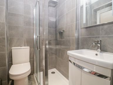 A bathroom with a toilet shower and sink with a mirror at Flat 2 38 Preston Road Weymouth