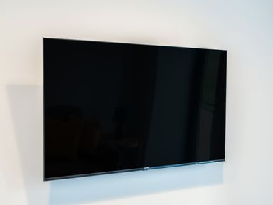 A black flat screen television mounted on a white wall at Tyddyn Haidd in Amlwch