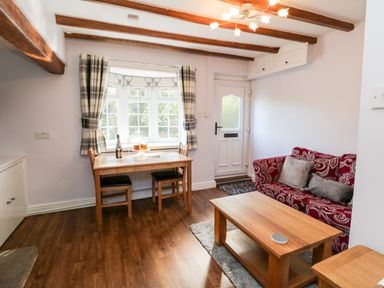 A living room with a red patterned sofa wooden coffee table and dining table near a window at Parva Great Broughton near Stokesley