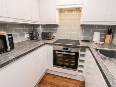 A kitchen with countertop appliances including microwave kettle and toaster an oven with stovetop a sink eggs knife block and paper towel at Parva Great Broughton near Stokesley