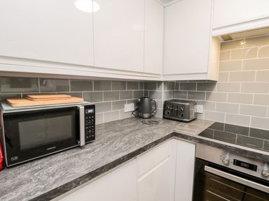 A kitchen counter with a microwave kettle toaster and stove at Parva in Great Broughton near Stokesley